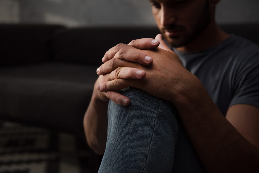 sad man sitting on floor at home, selective focus