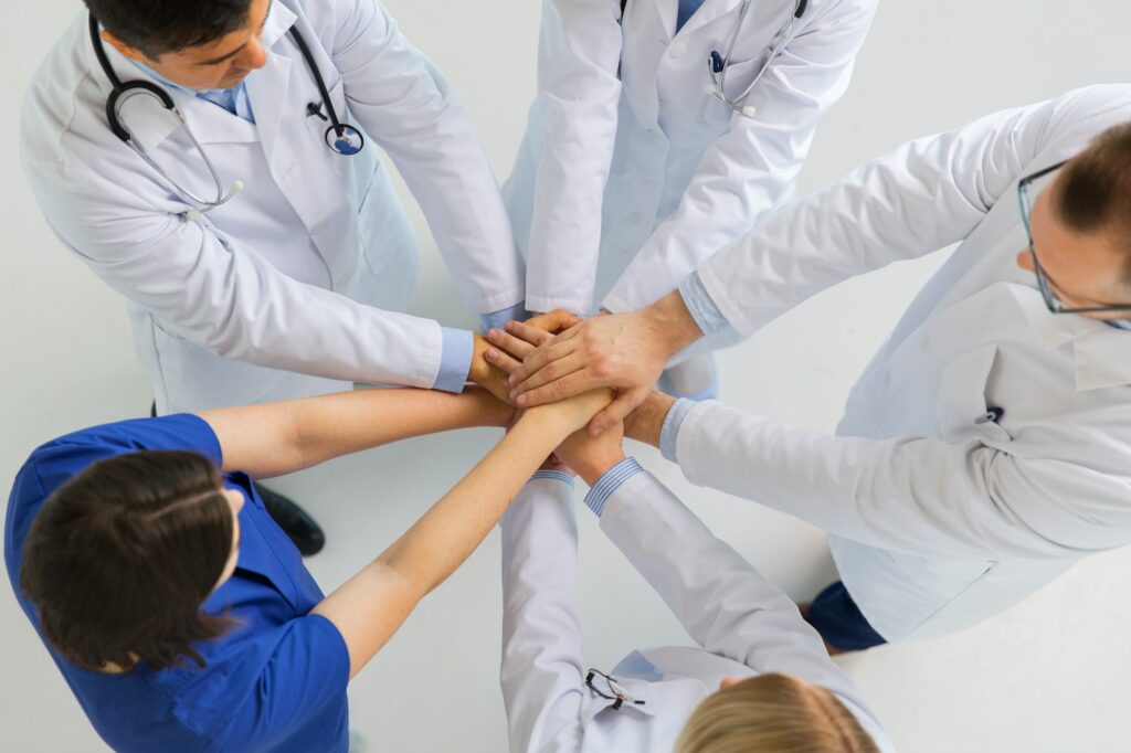 group of doctors with hands together at hospital